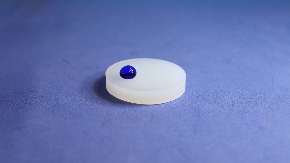 A plastic substrate has been treated with the new INP plasma process and is now water-repellent. A promising and environmentally friendly alternative to PFAS-based coatings. Plastic disc with blue drop