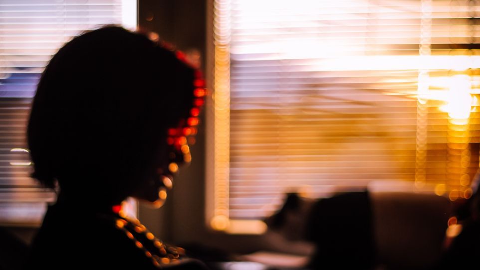 Frau am Fenster im Abendlicht, verschwommene Aufnahme.