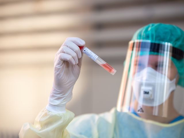A researcher in protective clothing examines a blood sample 