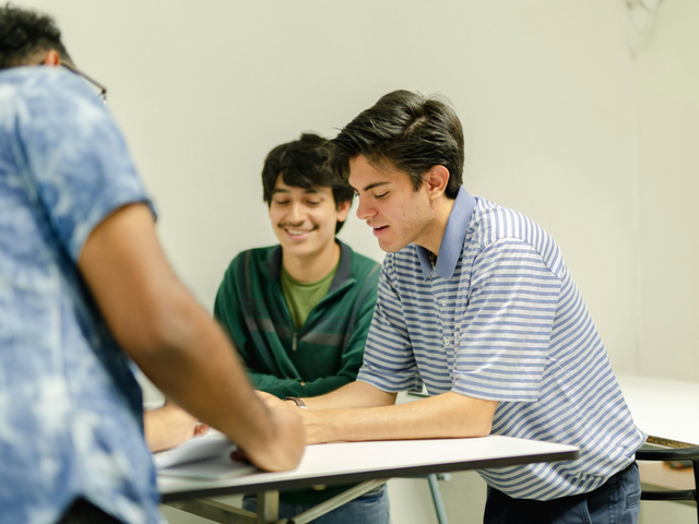 Drei Schüler sitzen an einem Tisch und unterhalten sich