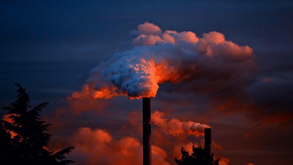 Fabrikkamin mit viel Rauch im roten Abendlicht