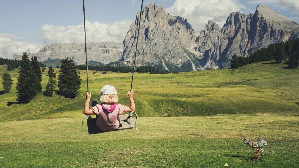 Kind auf einer Schaukel in den Bergen