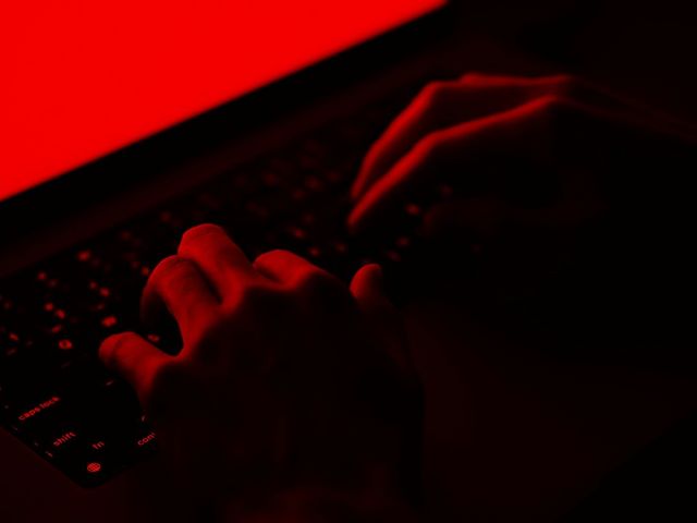 Hände auf Computertastatur mit roten Hintergrund