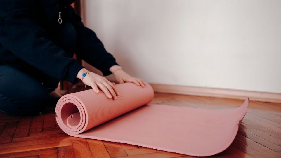 Person rollt Yogamatte aus