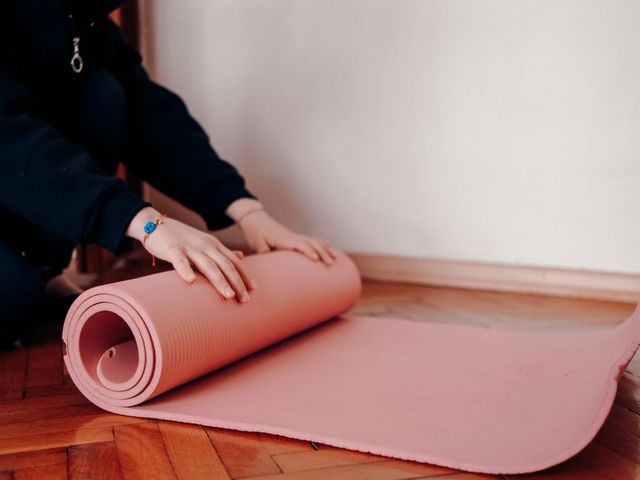 Person rollt Yogamatte aus