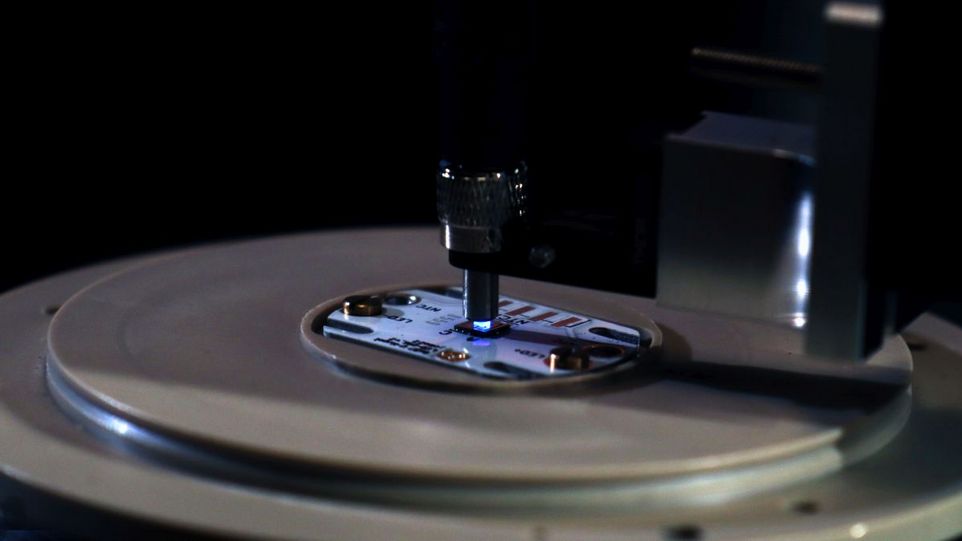 Laboraufbau mit Fern-UVC-LED-Chip bestehend aus Zehntausenden 235 nm Mikro-LEDs, die in eine Glasfaser emittieren. Runde Platte mit Chip, der von oben mit blauem Licht bestrahlt wird