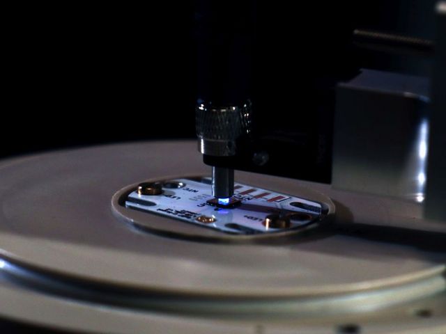 Runde Platte mit Chip, der von oben mit blauem Licht bestrahlt wird