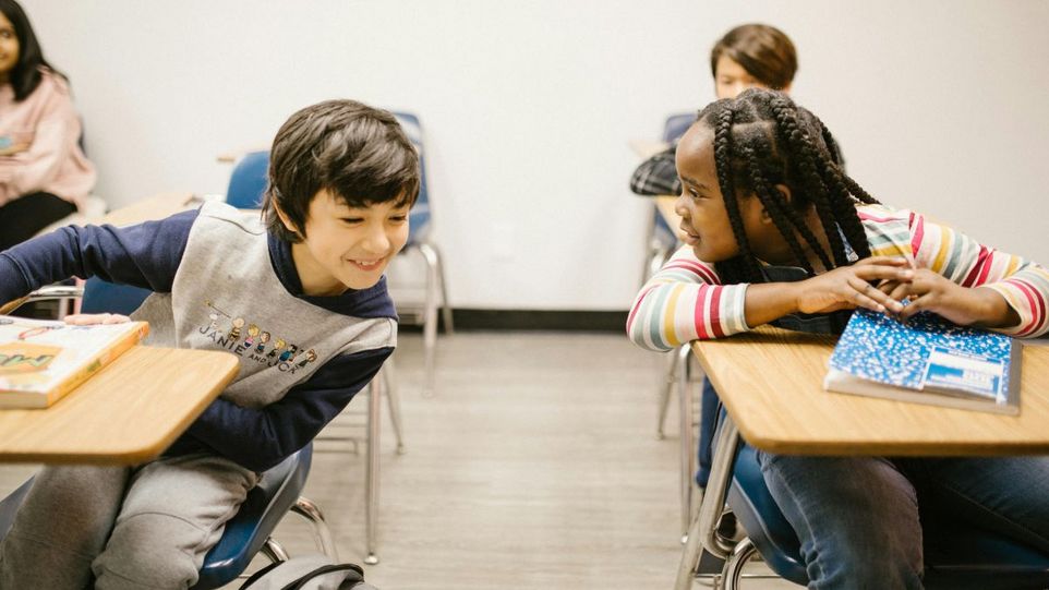 Eine Schülerin und ein Schüler sprechen im Klassenzimmer miteinander