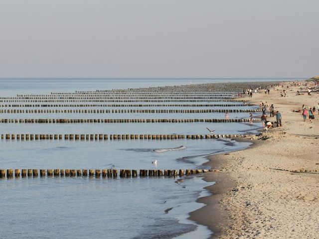 Gruppe von Menschen, die an einem Strand am Meer entlang spaziert