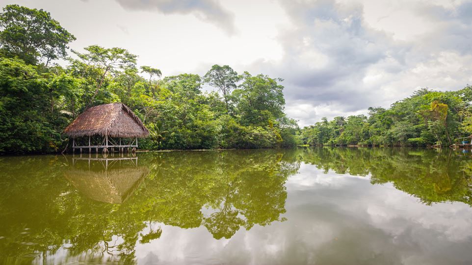 Amazonas mit spiegelnder Wasseroberfläche, im Hintergrund Steghaus