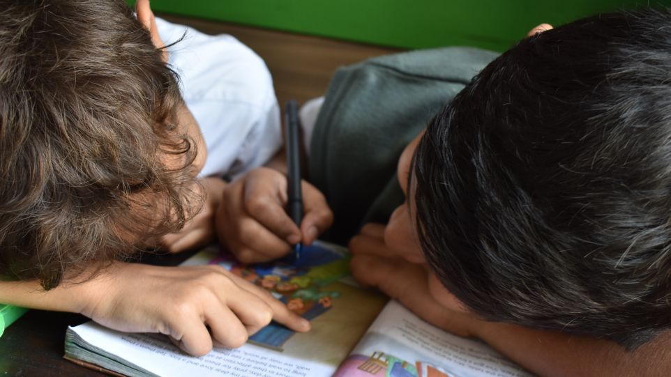 Two primary school pupils scribble in a school book
