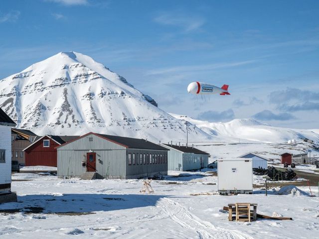 Fesselballon in verschneiter Berglandschaft, im Vordergrund eine Forschungstation