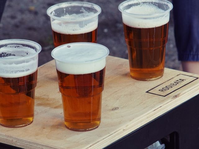 Vier mit Bier gefüllte Plastikbecher auf einem Tisch