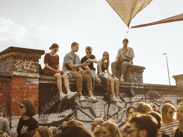 Junge Menschen sitzen auf einer Mauer in München