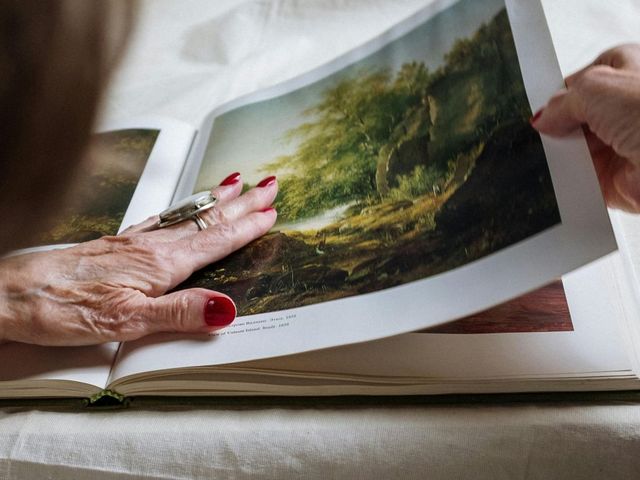 Hand einer alten Dame schlägt einen Kunstband auf