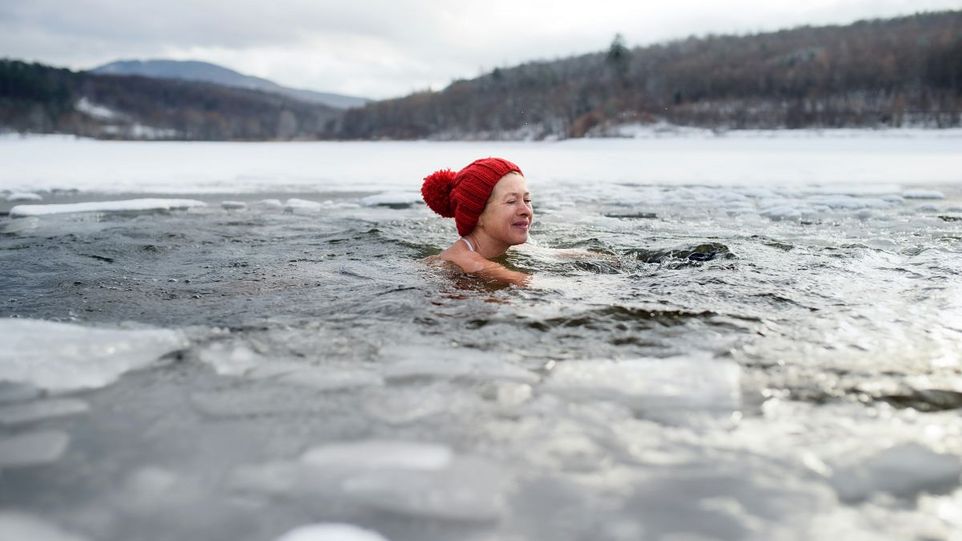 Frau mit Pudelmütze in einem Eisloch