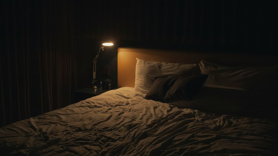 Ungemachtes Bett mit Nachtischlampe bei Nacht