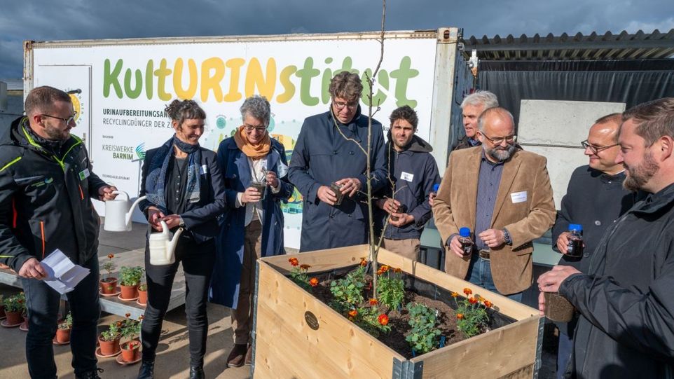 Menschen vor einem Blumenhochbeet