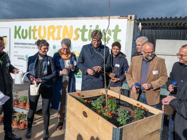 Menschen vor einem Blumenhochbeet