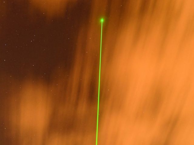 Grüner Laserstrahl vor orangem Hintergrund