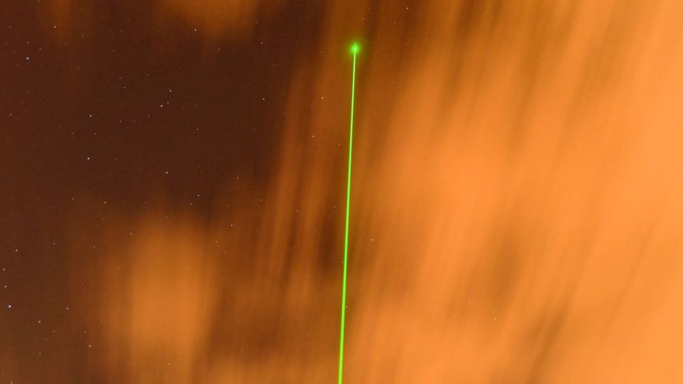 Grüner Laserstrahl vor orangem Hintergrund
