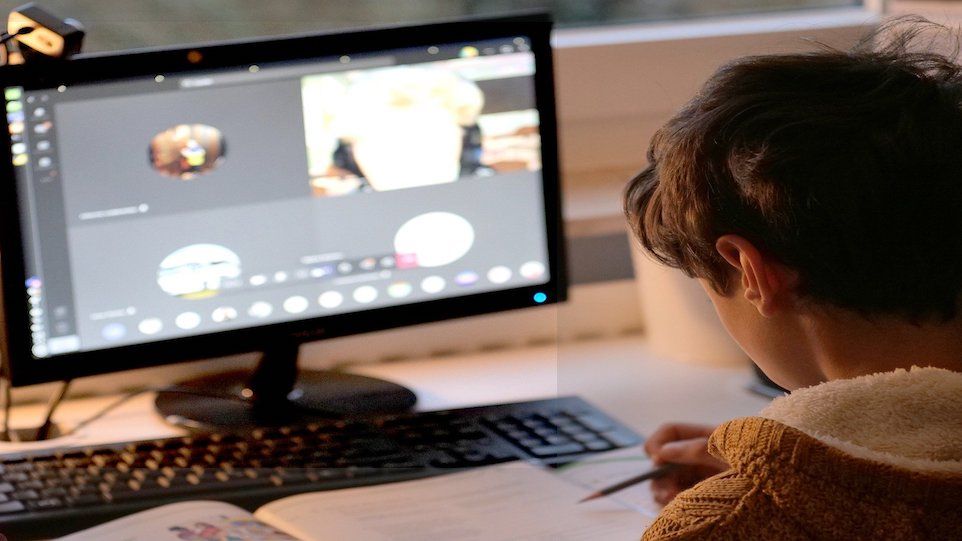 Schüler sitzt vor Bildschirm Zuhause und nimmt an einer Videokonferenz teil 