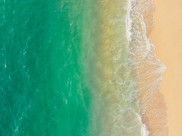 Türkisfarbenes Meer, das in sanften Wellen an einen Strand schlägt