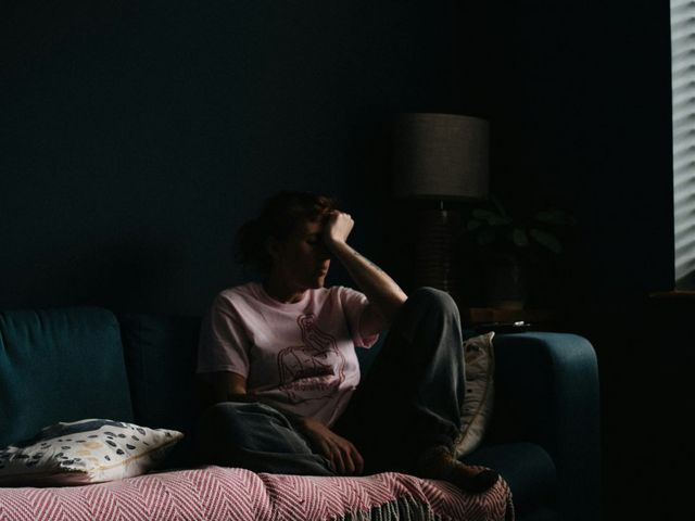 Frau auf Sofa, den Kopf in eine Hand gestützt
