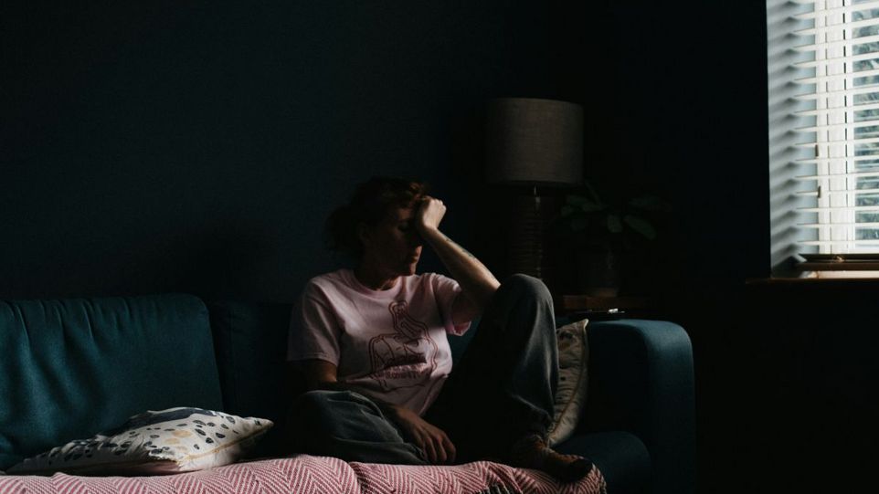 Frau auf Sofa, den Kopf in eine Hand gestützt