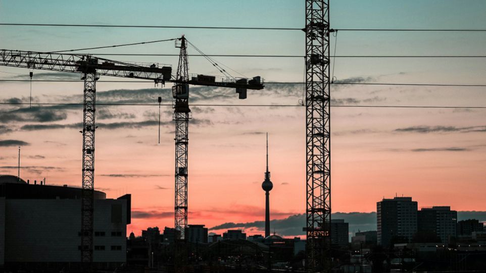 Berliner Skyline mit Fernsehturm und Baukränen in der Morgenröte