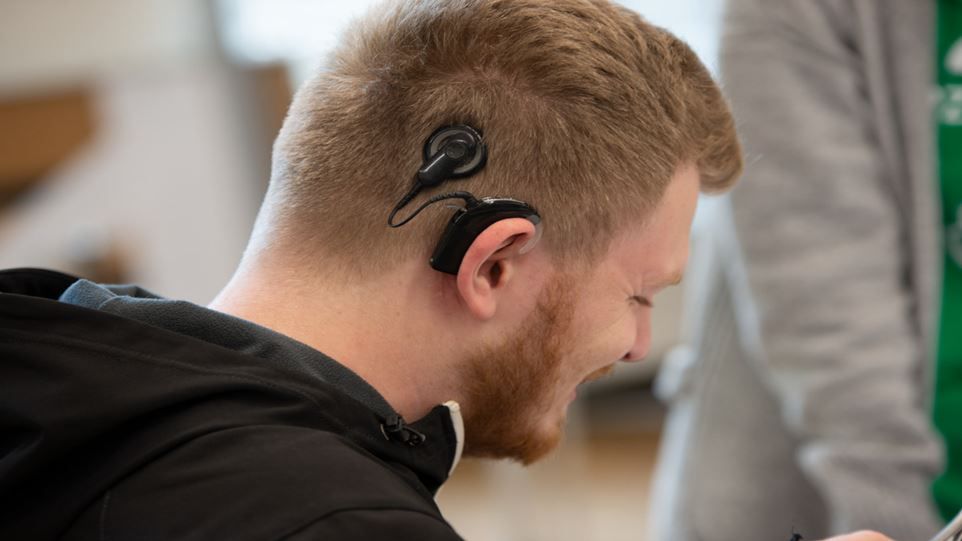 Junger Mann, welcher auf der rechten Kopfseite ein Cochlea-Implantat trägt.