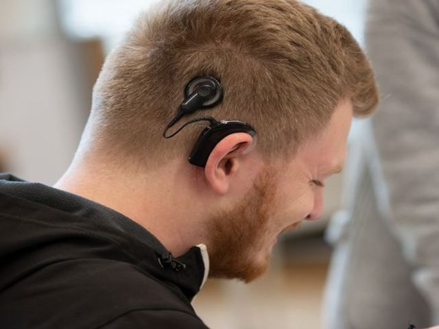 Junger Mann, welcher auf der rechten Kopfseite ein Cochlea-Implantat trägt.