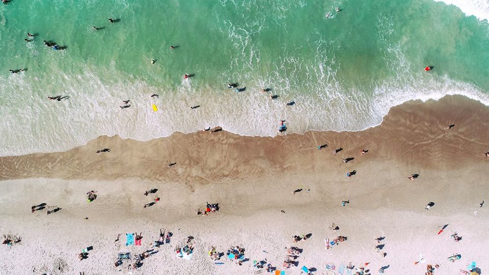 Luftansicht von einem Strand mit türkisem Wasser und Badenden