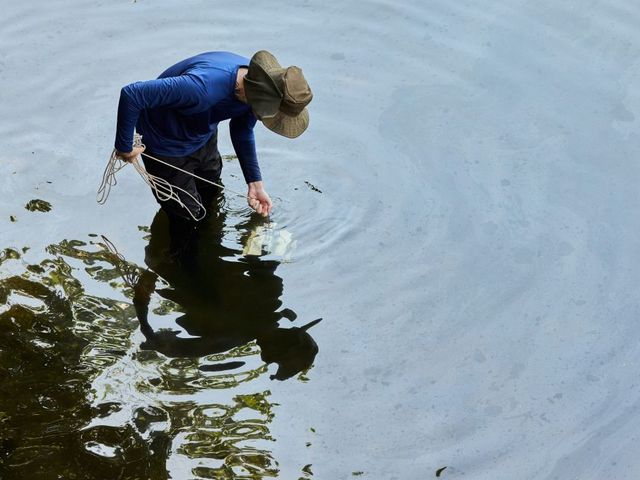 Mann lässt einen Kasten an einem Seil ins Wasser