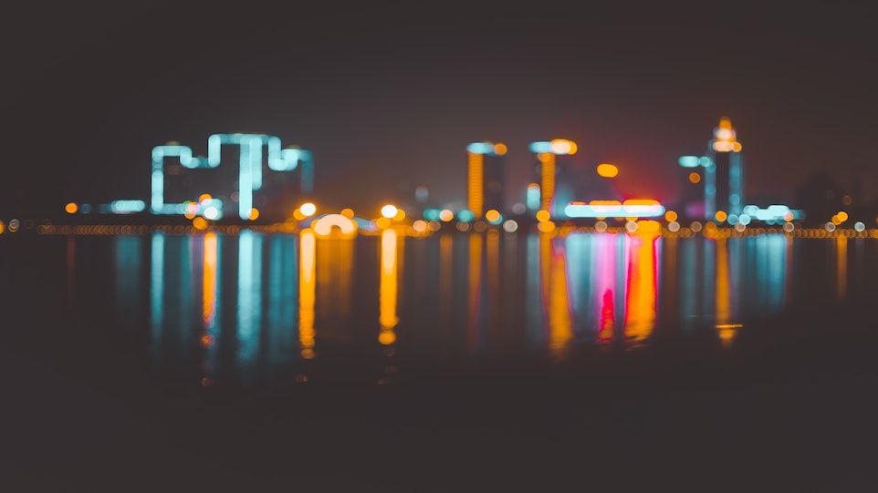 Beleuchtete Häuser, die sich in einem Fluss spiegeln.