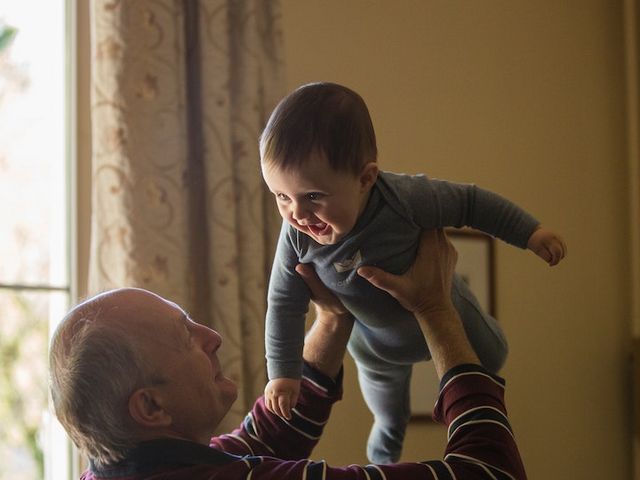 Elderly man holds toddler in the air