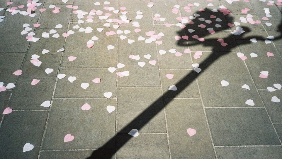 Rosa und weiße Papierherzchen auf dem Asphalt