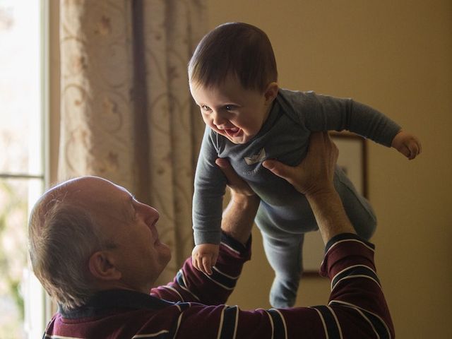 Elderly man stretches child in the air