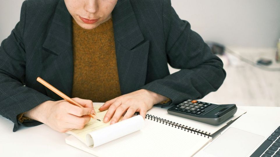 Frau mit Taschenrechner, Laptop und Formularen