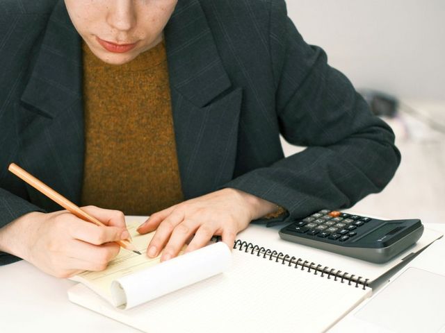 Frau mit Taschenrechner, Laptop und Formularen