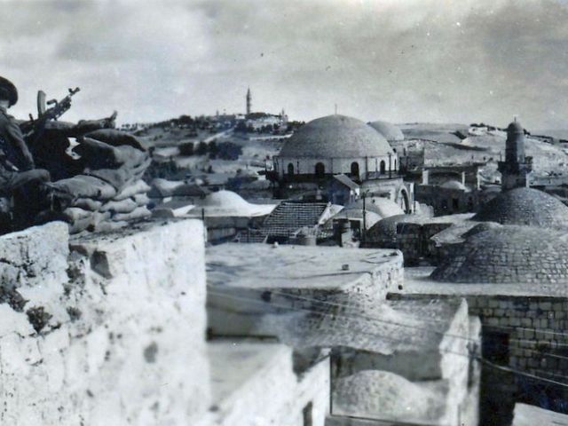 Schwarz-weiß-Fotografie eines britischen Soldaten mit Maschinengewehr, der auf Jerusalem blickt (1948)