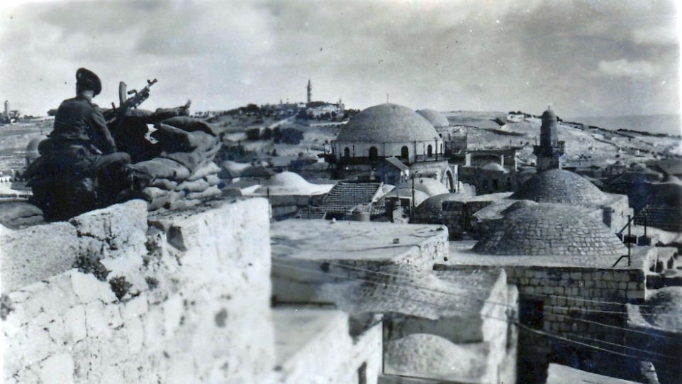Schwarz-weiß-Fotografie eines britischen Soldaten mit Maschinengewehr, der auf Jerusalem blickt (1948)