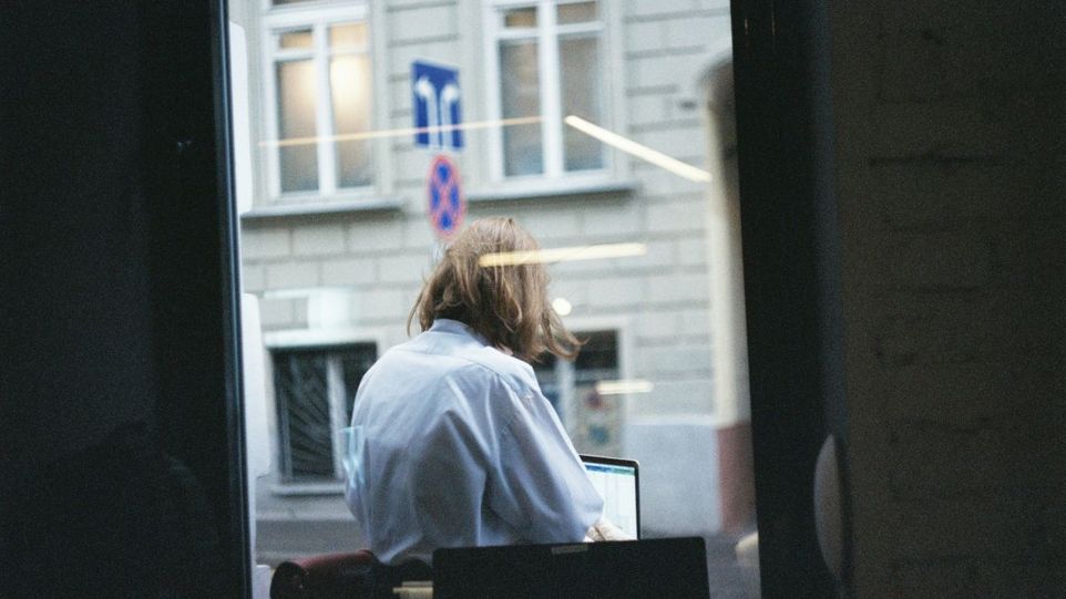 Frau am Laptop, durch ein Fenster gesehen