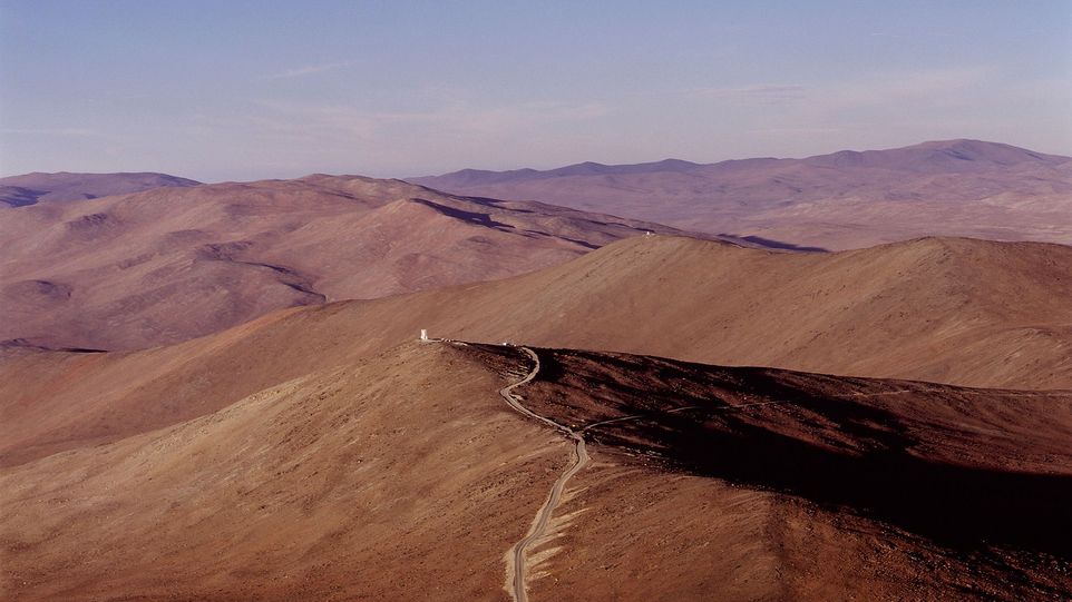 Kahle Berglandschaft mit einem Weg, der auf ein Gebäude in der Ferne zuläuft