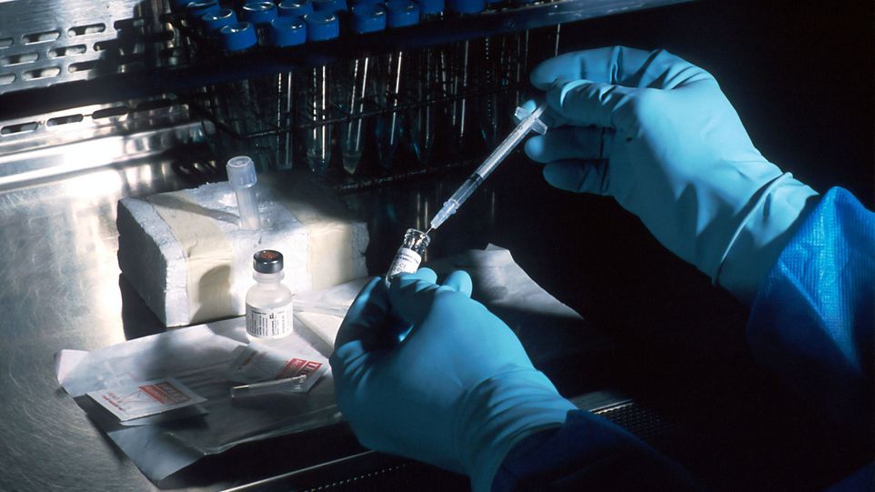 Hände in sterilen Handschuhen bereiten eine Spritze vor.