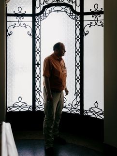 Ein Mann steht im Profil vor einer hohen, ornamentierten Glastür mit schmiedeeisernen Verzierungen. Das Gegenlicht lässt ihn als Silhouette erscheinen. Der Mann ist der Wissenschaftler Peter Mario Kreuter.