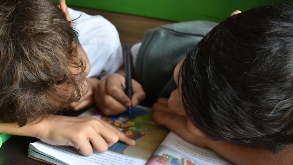 Zwei Jungen beugen sich über ein Schulbuch