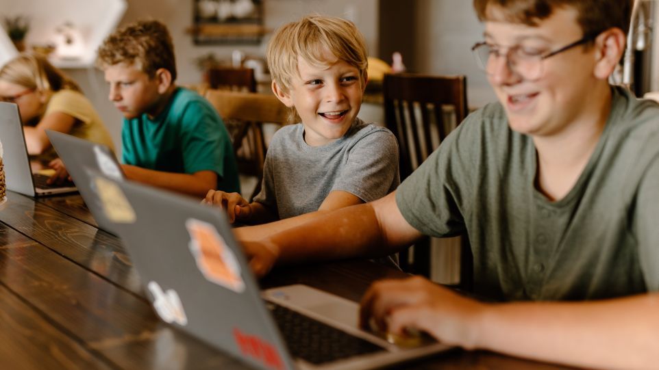 Vier Schüler mit Laptops an einem Holztisch