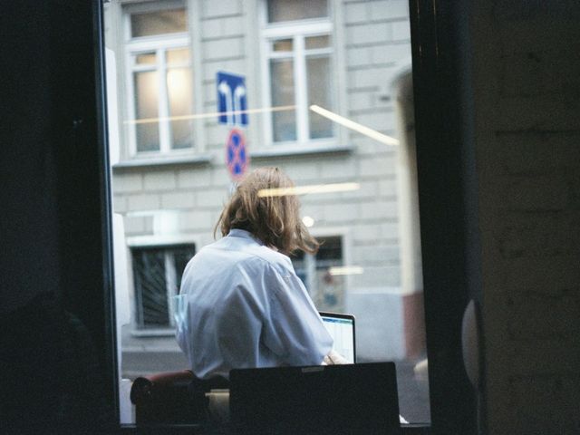 Frau am Laptop, durchs Fenster gesehen