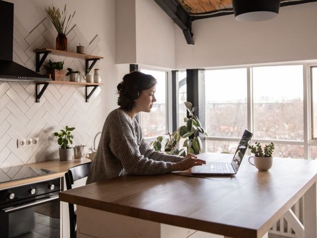 Home office is becoming established Woman working on the laptop at the kitchen table